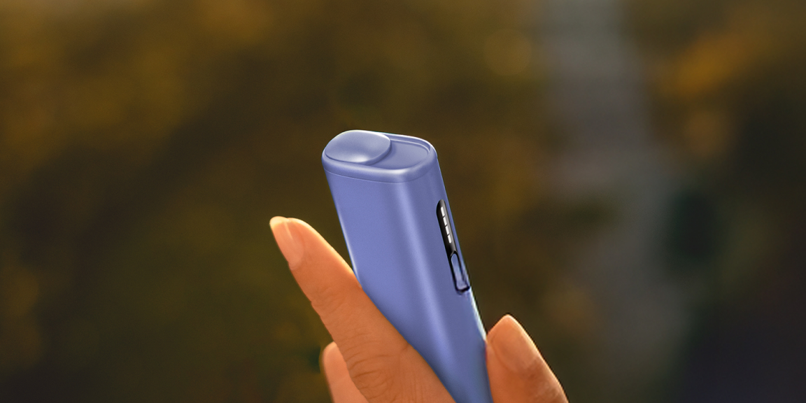 Blue IQOS ILUMA i device and a phone on a table